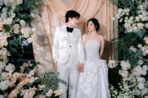 Elegant multicultural wedding couple during ceremony with floral arch and romantic styling.