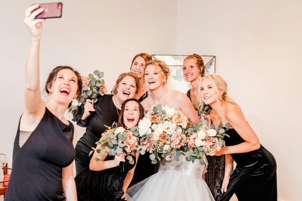 Bride and bridesmaids taking a joyful selfie in a luxury hotel wedding in Milan, Italy.
